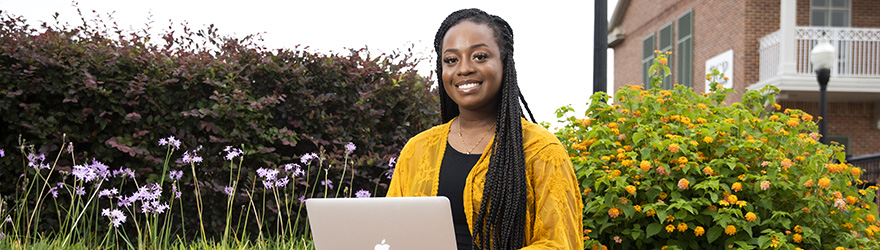 A Student Smiles While Using A Laptop Downtown